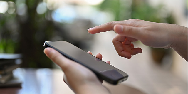 Hand pointing at a smartphone, ready to send pictures to Askin for dermatologist consultation.